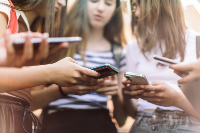 Teenage Girls Have Fun And Conversation Using Their Mobile Phones